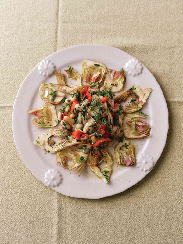 Artichoke and white bean salad with herbs and roasted peppers on a white plate