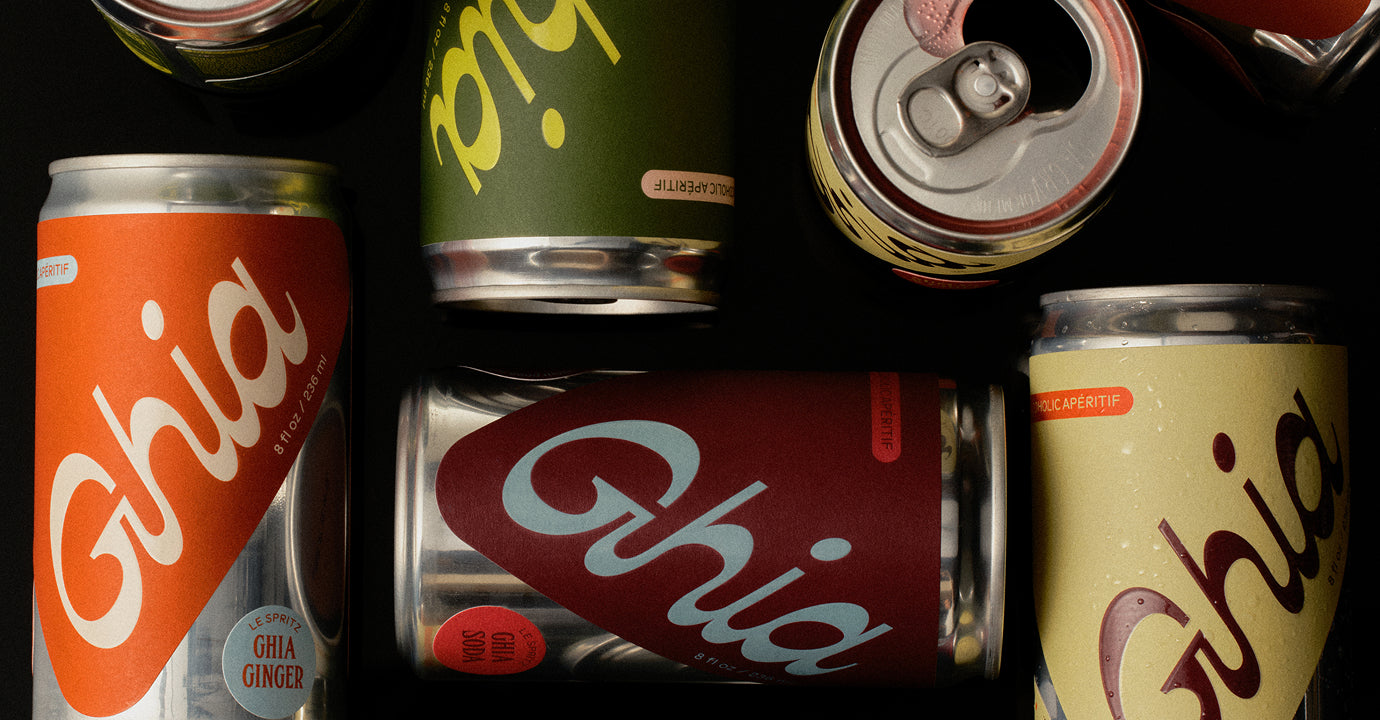 Colorful Ghia Le Spritz cans in assorted flavors scattered on a black background