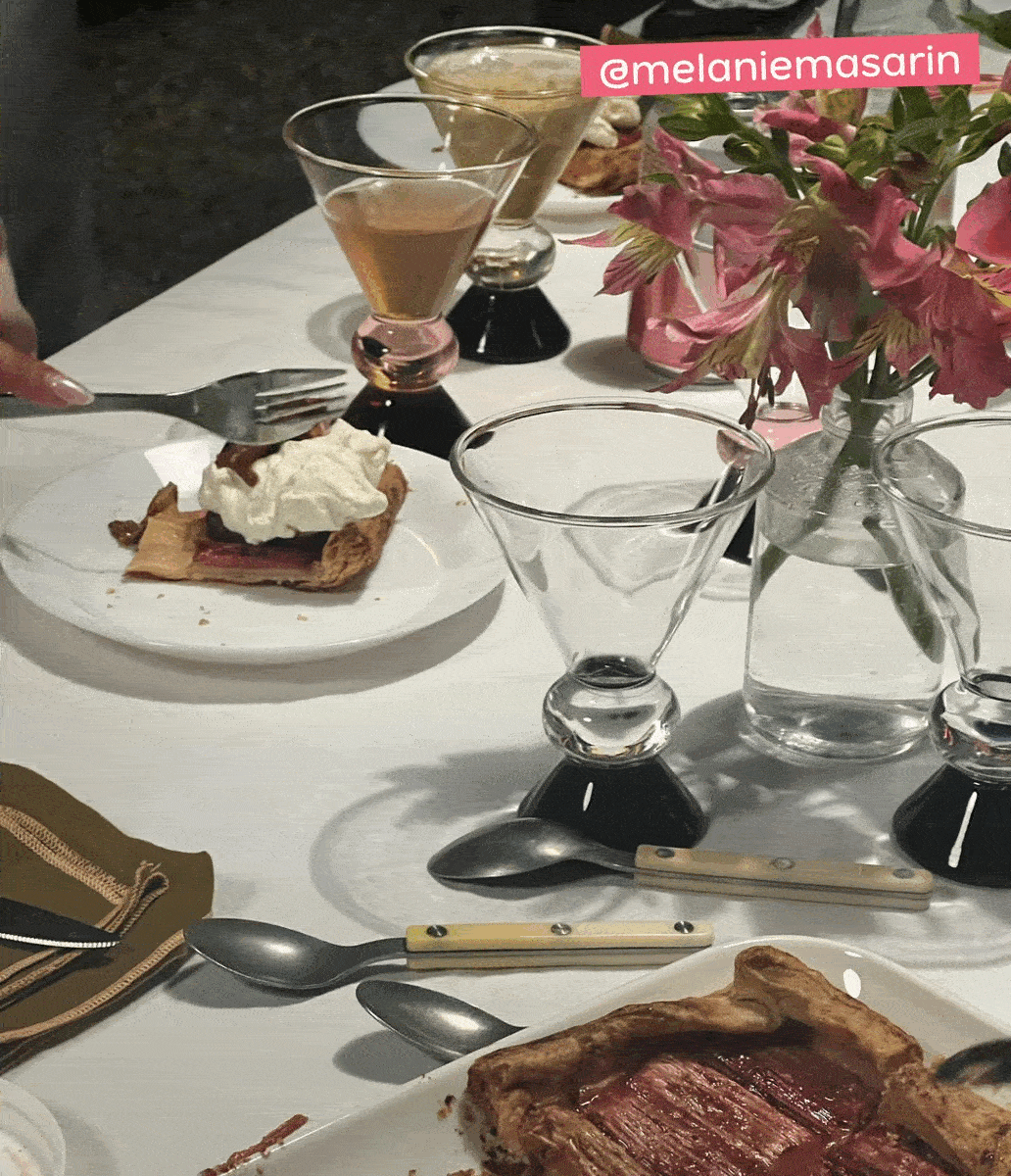 Table set with Ghia totem glasses, galette, and pink flowers, tagged @melaniemasarin